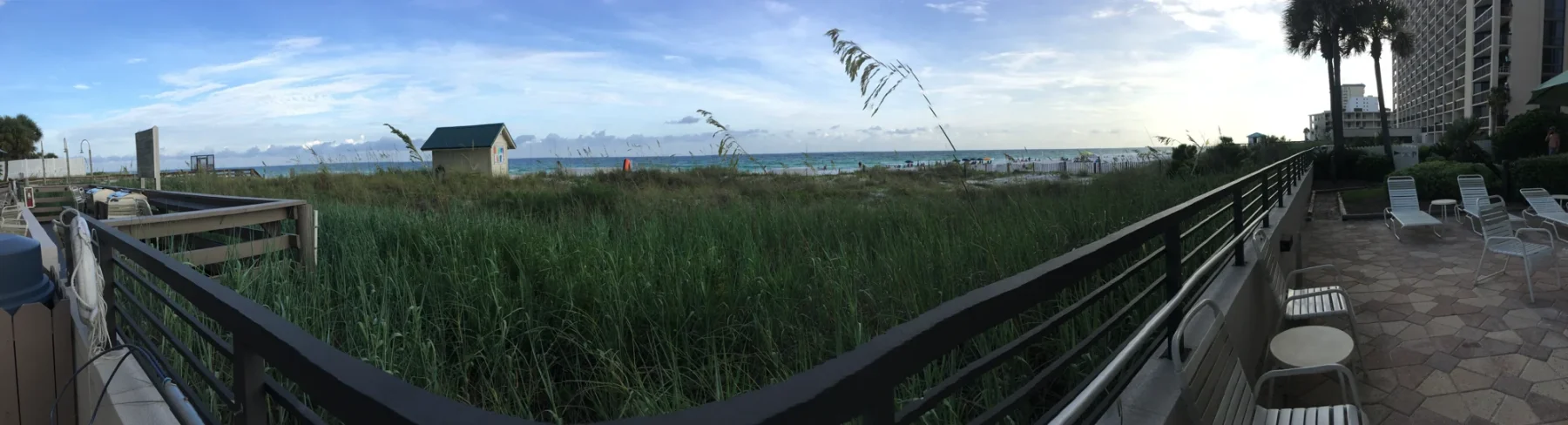A beach boardwalk with dune vegetation and water beyond in Destin