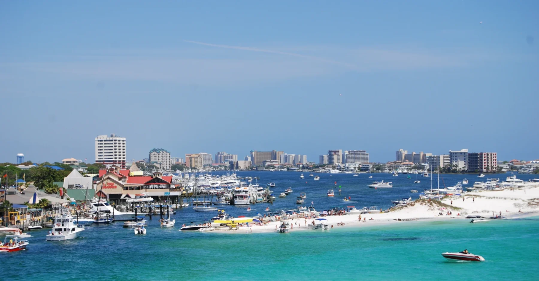 Boats, waterfront buildings and the shoreline around Destin Harbor